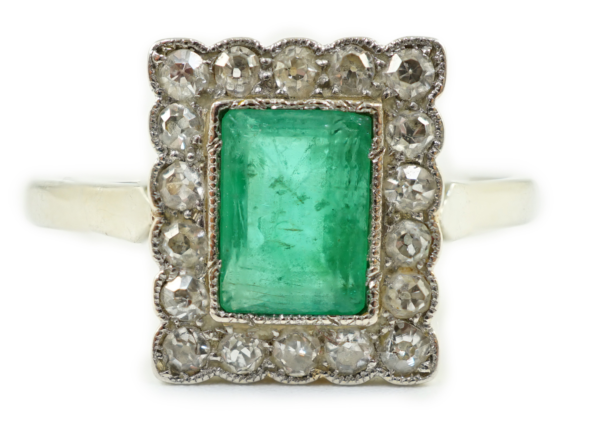 A 1920's 18ct white gold and platinum, emerald and millegrain set diamond rectangular cluster ring